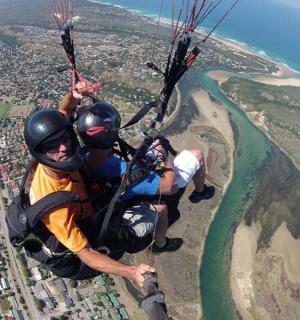 two people hanging from a parachute over the ocean