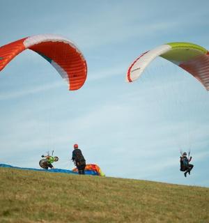 skupina lidí pouštějících draky na kopci