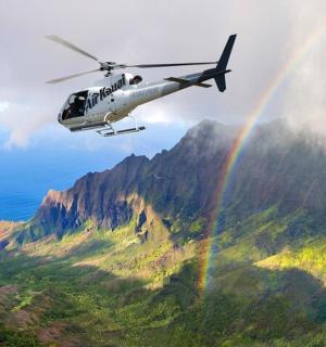 vrtulník letící nad horou s duhou