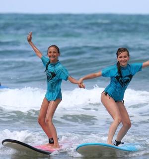 zwei junge Mädchen reiten auf Surfbrettern im Meer