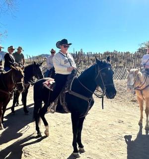 skupina lidí jezdících na koních po nezpevněné cestě