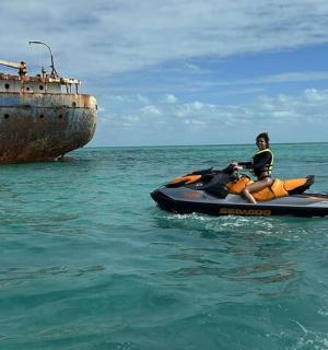 一名女子在船旁的水中驾驶水上摩托艇