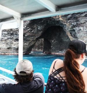 dva lidé na lodi pozorují medvěda ve vodě