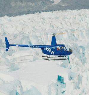 Modrý vrtulník letí nad ledovcem