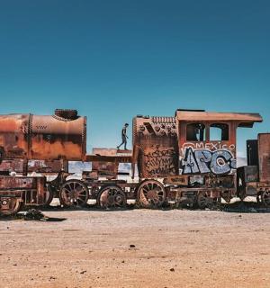 an old rusty train sitting in the desert