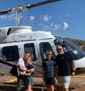 skupina lidí stojící před vrtulníkem