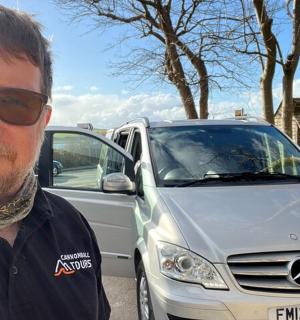 一名戴着墨镜的男子站在汽车旁边