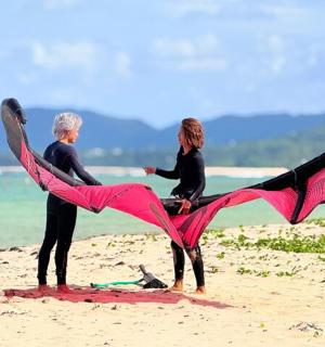 two people standing on the beach holding a kite