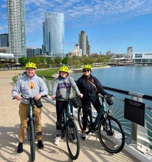 三个人骑着自行车在水边的桥上