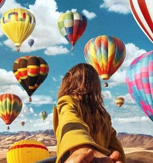 a woman is looking at a bunch of hot air balloons