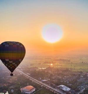 balon na ogrzane powietrze lecący nad miastem o zachodzie słońca
