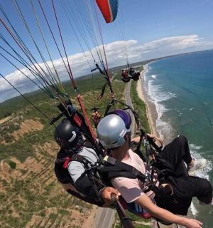 skupina lidí letících na padáku nad oceánem