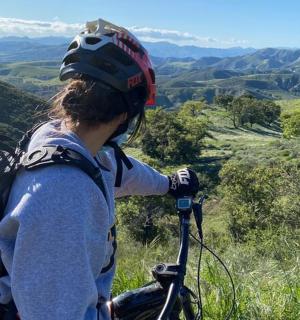 a person with a backpack standing on a bike on a hill