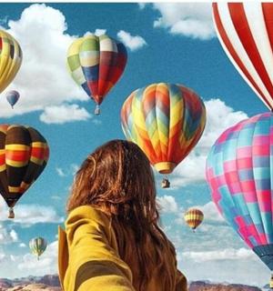 a woman looking up at a bunch of hot air balloons