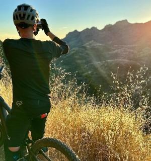 a man on a bike looking at the sunset