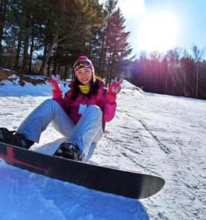 a woman sitting in the snow on a snowboard