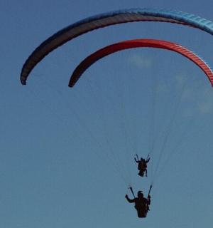 muž letí s padákem na obloze