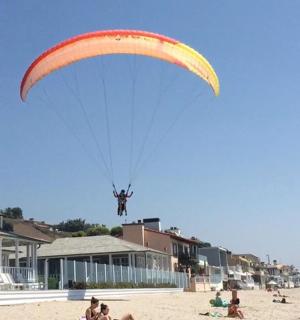 a person flying a large parachute on the beach