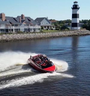a group of people on a boat in the water with a lighthouse