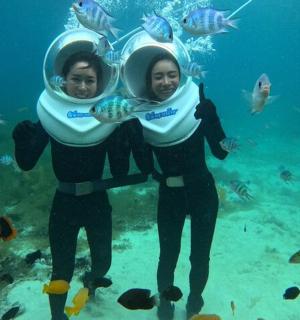 two women standing under the water with fish