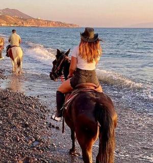 a group of people riding horses on the beach