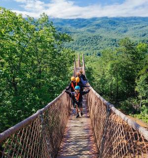 skupina lidí jdoucích po visutém mostě