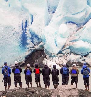 skupina lidí stojících na skále před ledovcem
