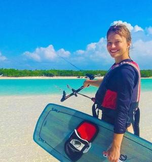 一名男子站在海滩上，手里拿着冲浪板和风筝