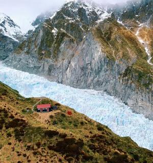 a house on the side of a mountain next to a river