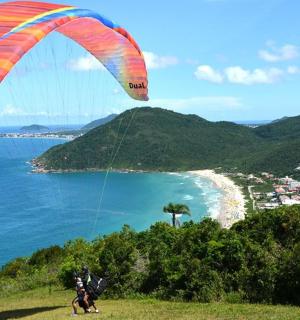 a person flying a kite on a hill near the ocean