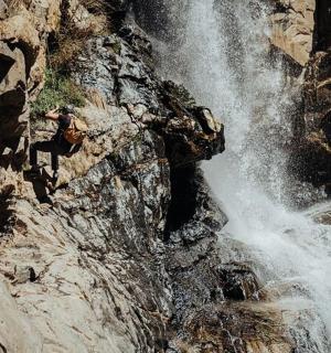 osoba stojící vedle vodopádu na hoře
