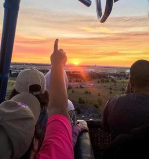 Skupina lidí sedících v tramvaji a dívajících se na západ slunce