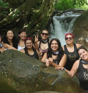 a group of people posing in front of a waterfall