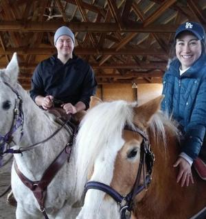 two people riding on horses in a barn