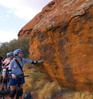 skupina lidí jedoucích na segwayích vedle skály