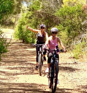 两名女子骑着自行车沿着泥土小路前行