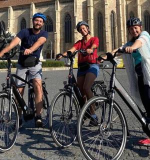 drei Personen auf Fahrrädern vor einer Statue