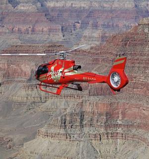 a red helicopter flying over the grand canyon