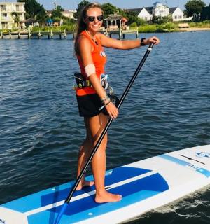 一名女子站在水中的桨板上