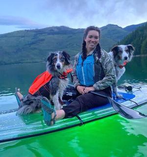 一位女士和两只狗坐在桨板上