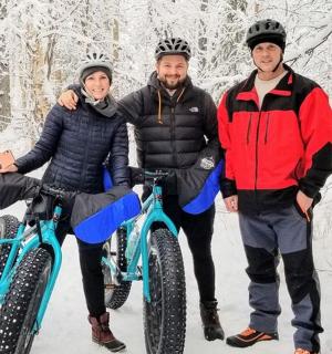 three people posing with their bikes in the snow