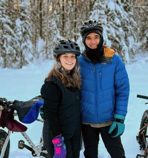 a man and a woman standing next to bikes in the snow