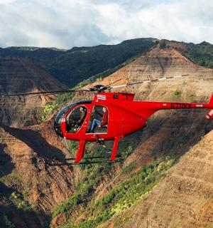 Červený vrtulník letí nad horou