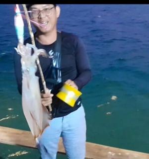 isang binata na may hawak na isda sa bangka