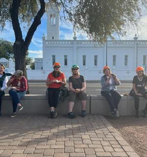 skupina lidí sedících na zdi před budovou