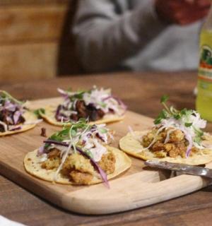 tři tacos na prkénku na stole