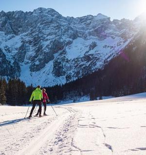 dva lidé na lyžích ve sněhu před horou
