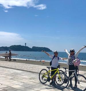 两名女子站在海滩上的自行车旁