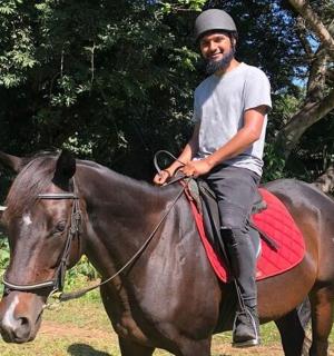 muž sedí na hnědém koni