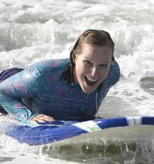 žena ležící na surfovém prkně ve vodě